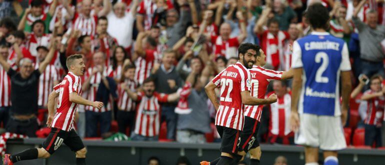 El jugador del Athletic de Bilbao Aritz Aduriz (3i) celebra el segundo gol para su equipo junto a Raúl García (c) e Iker Muniain (i) frente al jugador de la Real Sociedad, Iñigo Martínez (d), en el partido correspondiente a la octava jornada de liga Santa
