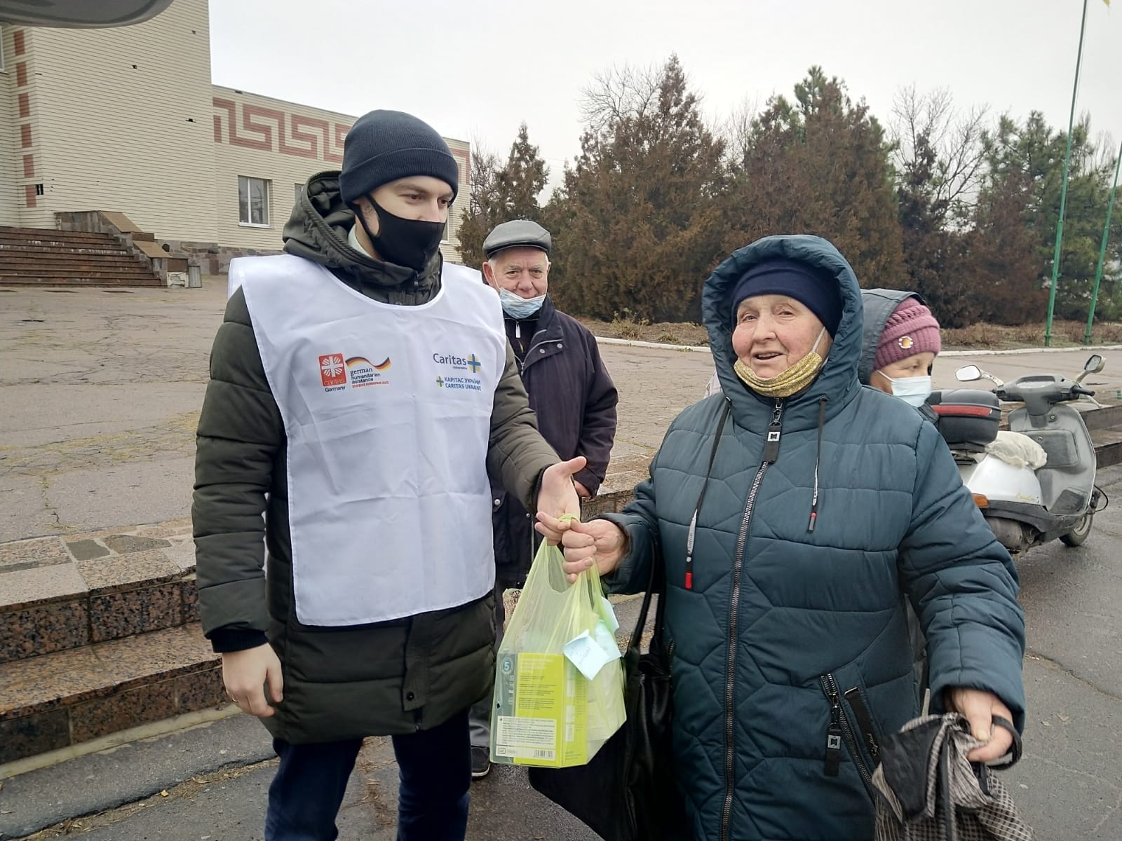 Un miembro de Cáritas entrega ayuda humanitaria a una mujer ucraniana