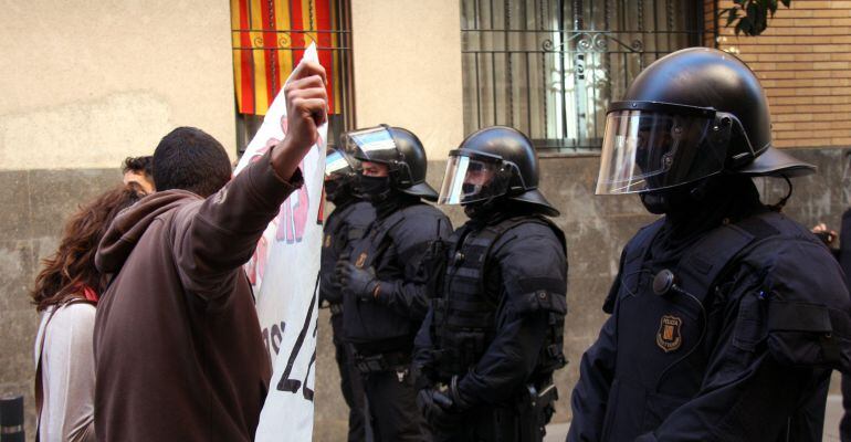 Primer pla d'una concentració de joves anarquistes davant d'un cordó d'antiavalots dels Mossos, al barri de Sants (horitzontal).