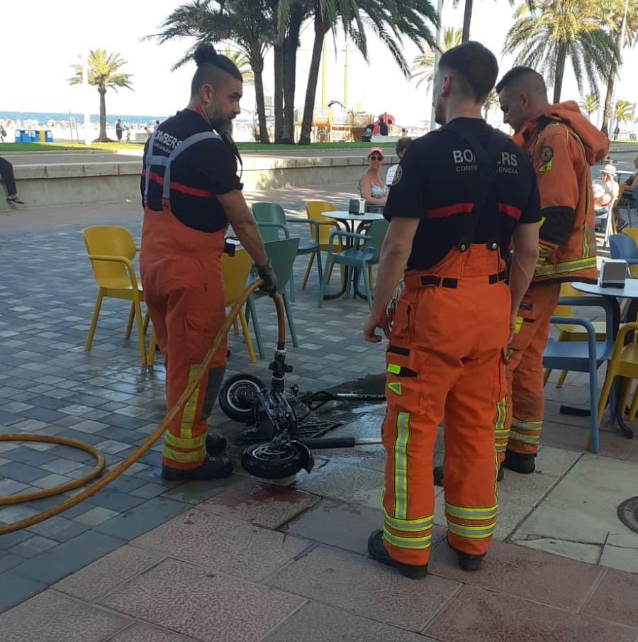 Bomberos trabajando en la extinción del incendio de un patinete en la playa Nord de Gandia.