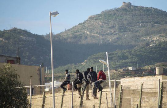 African migrants sit at the top of a border fence during an attempt to cross into Spanish territories, between Morocco and Spain&#039;s north African enclave of Melilla December 30, 2014. Of the nearly 200 migrants who participated in the attempt, 102 migrants