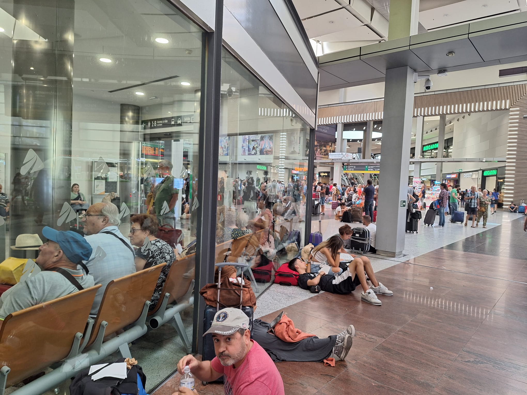 Colas y viajeros tirados por los suelos ante la oficina de atención al cliente de AVE en Málaga