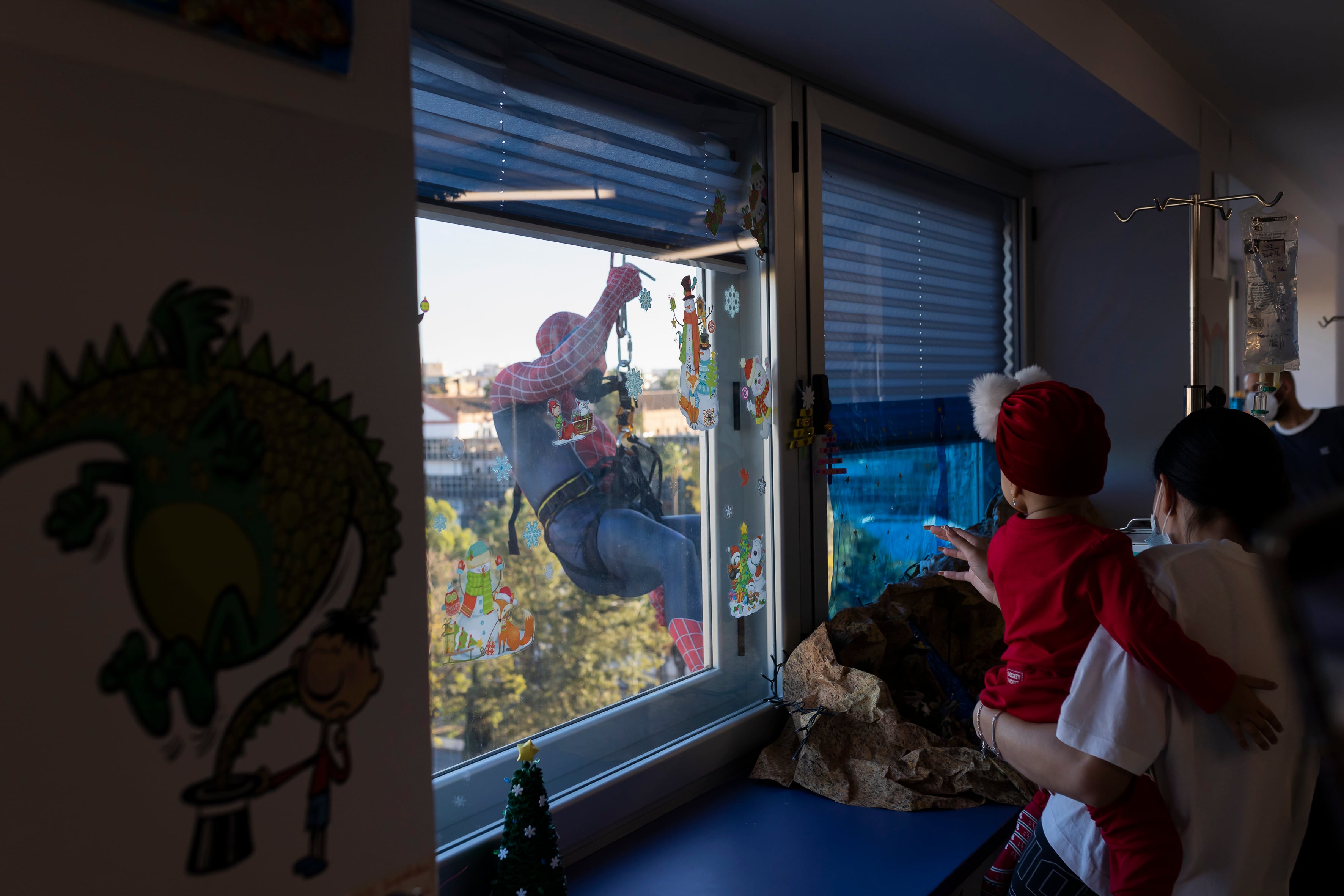 GRAFAND7551. MÁLAGA, 18/12/2023.- Spiderman se ha descolgado por la fachada del Hospital Materno de Málaga, desde el tejado con la ayuda de un bombero, para saludar a los niños ingresados en las plantas de enfermedades infecciosas, Oncología, Lactantes y Cirugía a través de las ventanas. EFE/Carlos Díaz
