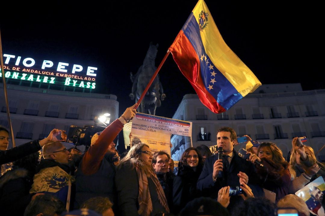 El líder del PP Pablo Casado (d) y decenas de venezolanos se concentran en la madrileña Puerta del Sol tras conocer que el presidente del Parlamento venezolano Juan Guaidó se ha autoproclamado jefe de Estado de Venezuela.