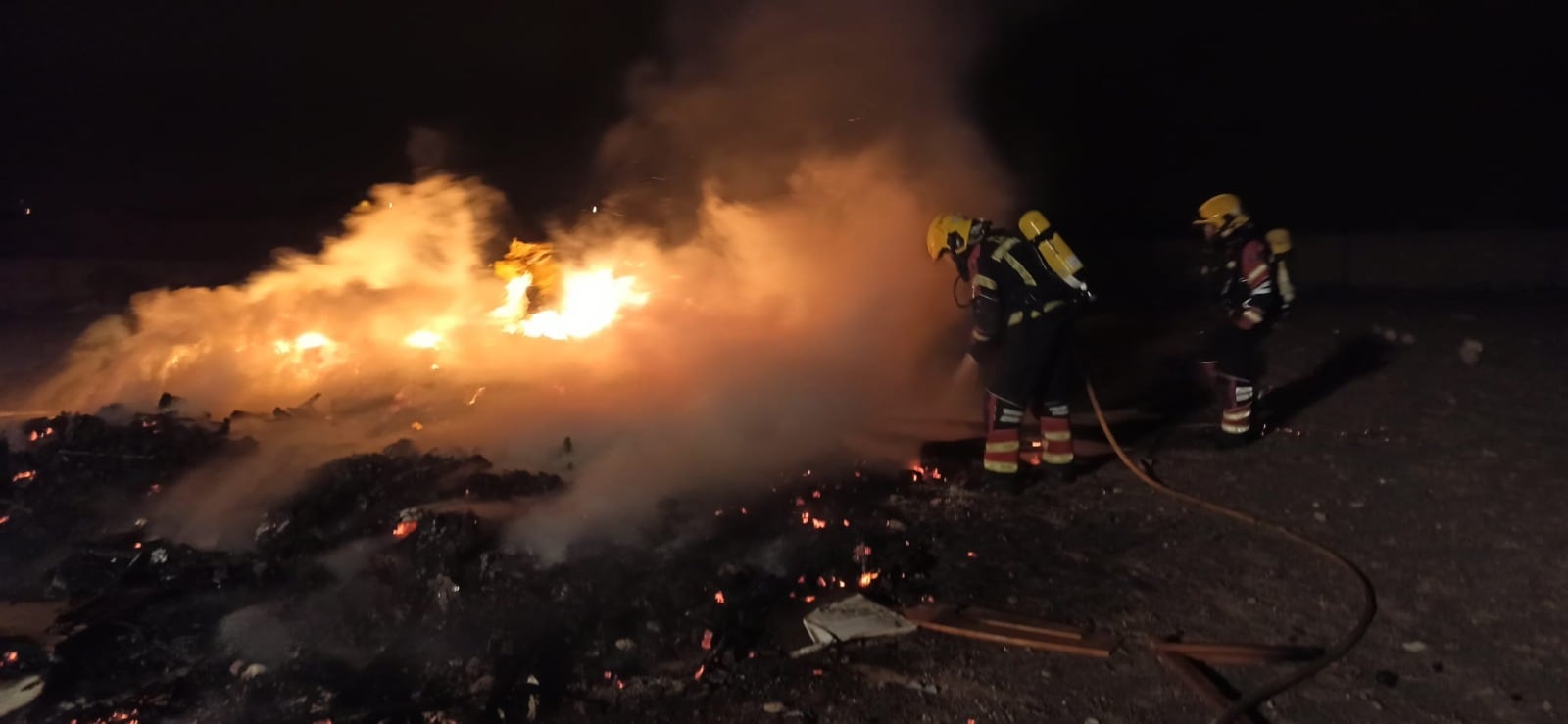 Los bomberos apagando el fuego de la hoguera.