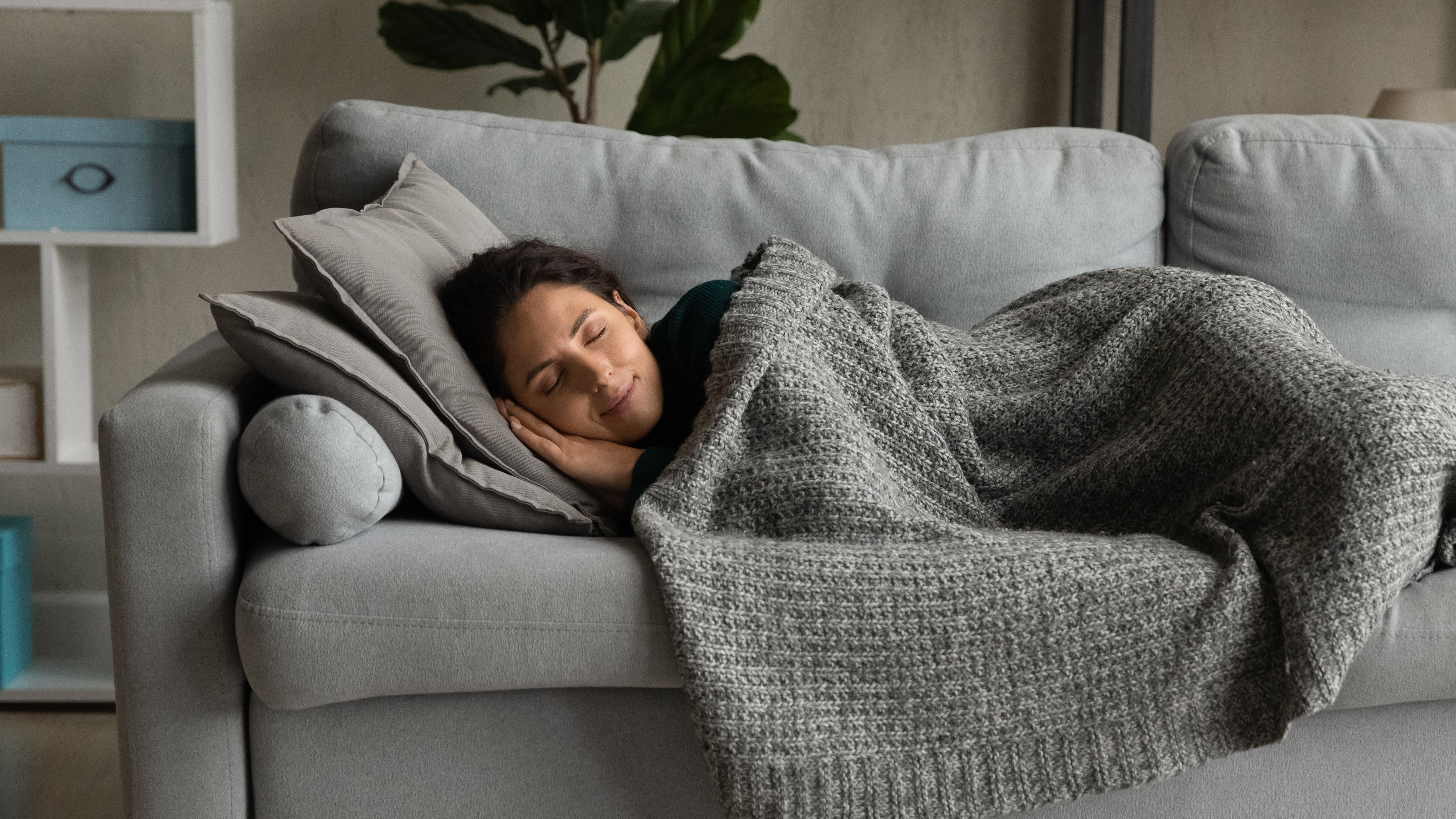 Una mujer duerme con una manta en el sofá