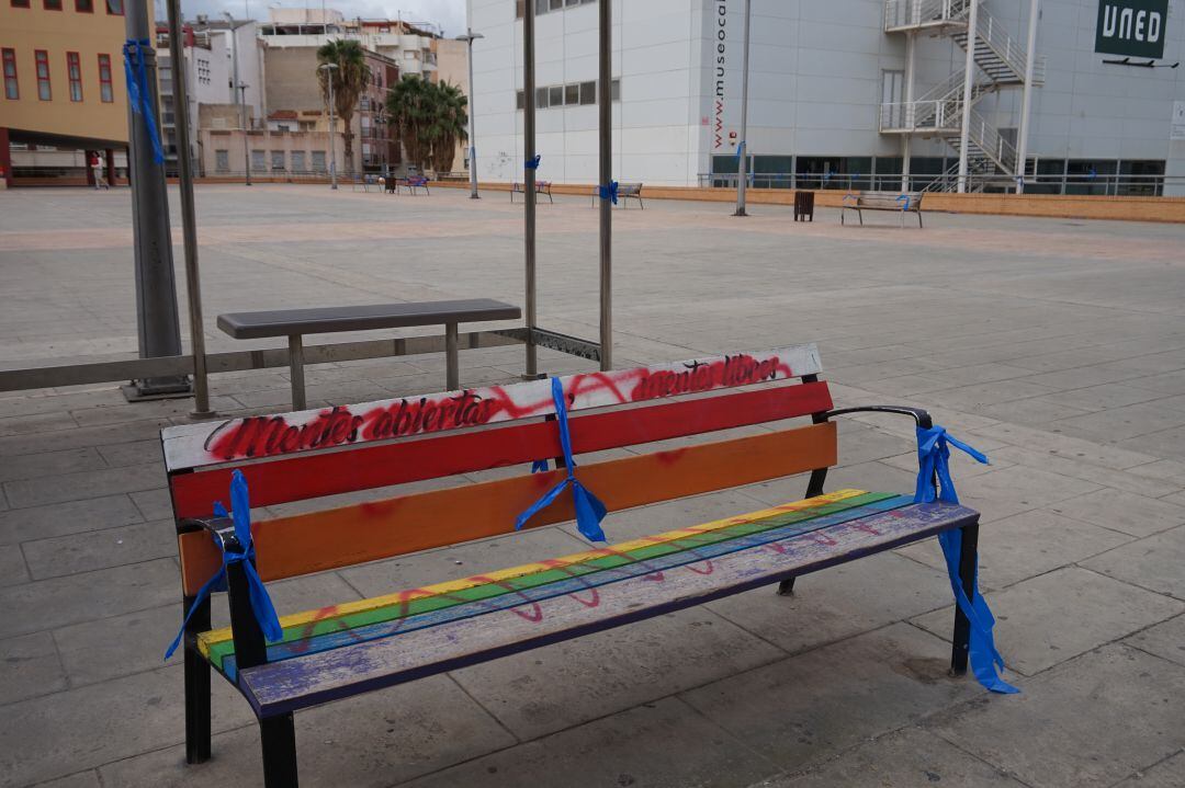 Banco de la Plaza de la Ficia con lazos azules y con los mensajes a favor del movimiento LGTB tachados 