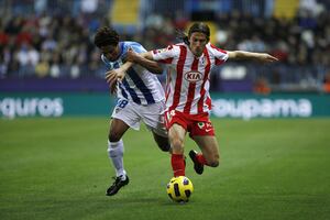 El lateral brasileño del Atlético de Madrid se lleva un balón ante la presión de un jugador del Málaga