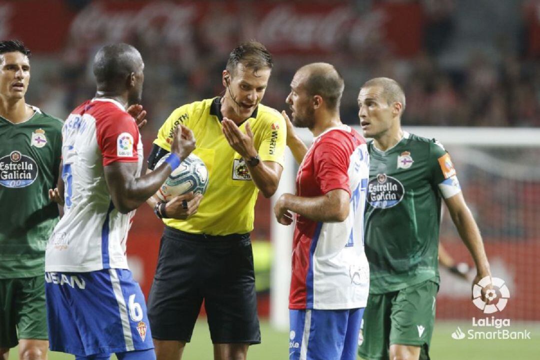 El árbitro señala el penalti ante las protestas de los jugadores del Sporting.