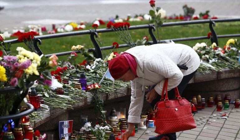 A woman lights candles to commemorate victims of the Paris attacks, in front of the French embassy in Minsk