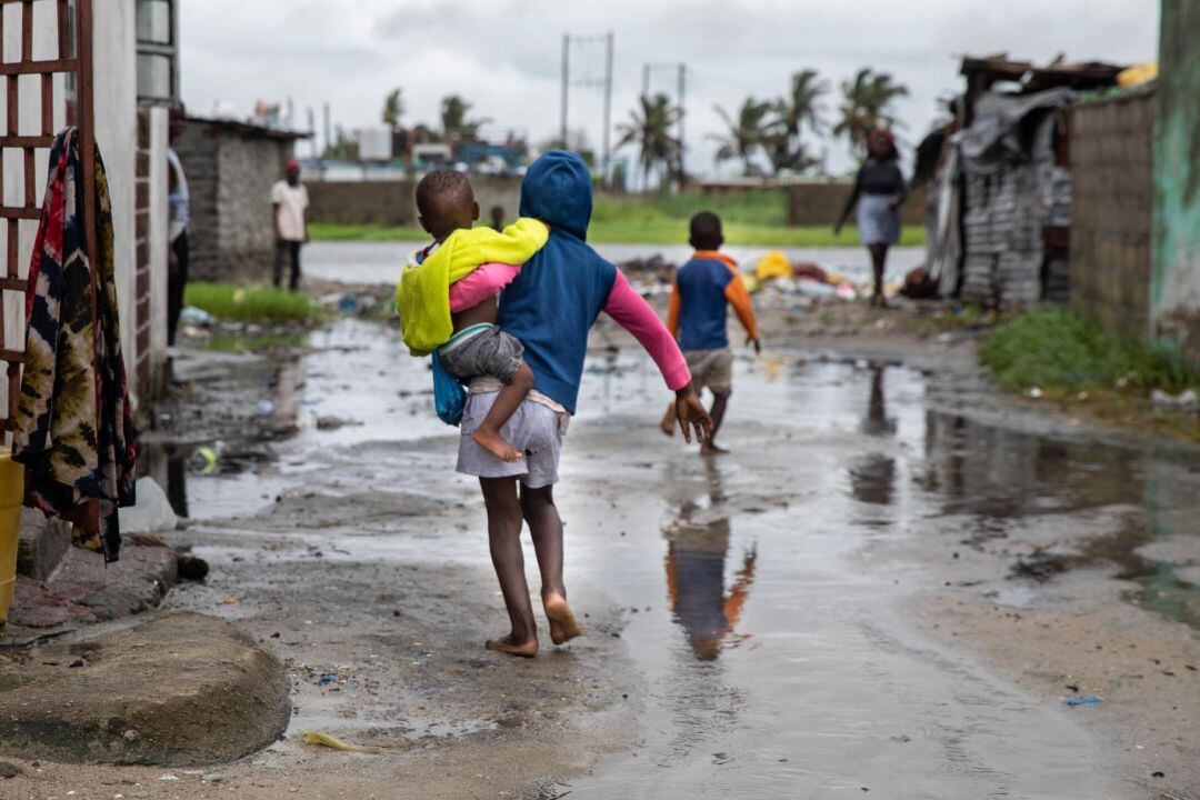 Fotografía cedida por Unicef que muestra a niños mientras caminan por una calle inundada el 22 de enero de 2021, tras el paso del ciclón Eloise, en el barrio Praia Nova de Beira (Mozambique). 