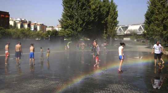 Grandes y chicos se refrescan en una de las fuentes del parque Madrid Río para combatir las altas temperaturas.