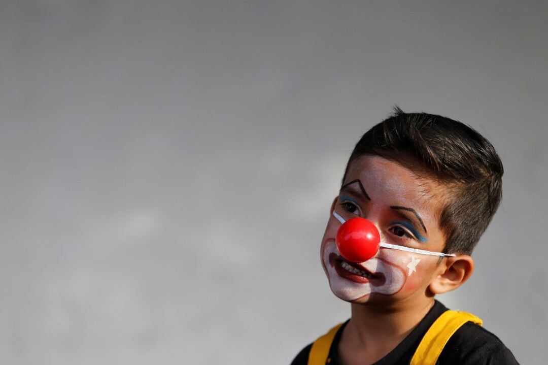 Un niño vestido de payaso sonríe 