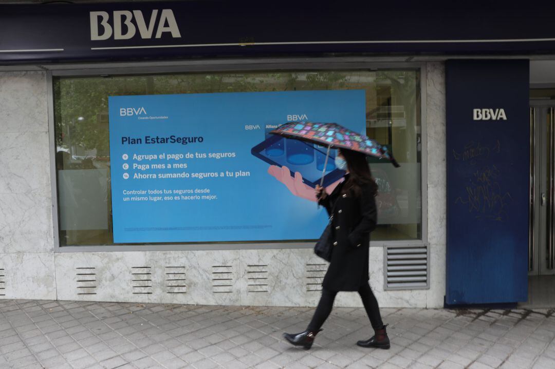 Una persona pasa por delante de la puerta de una Oficina de BBVA.