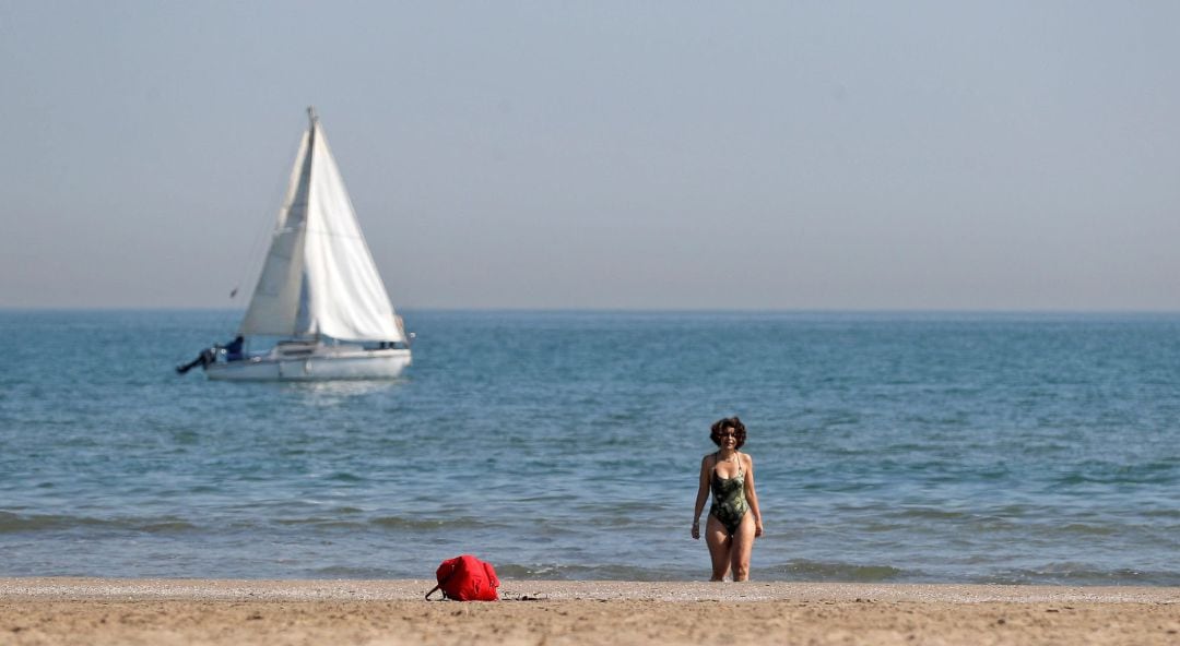 Una jóven disfruta del sol y las temperaturas por encima de los veinte grados este viernes en la playa de la Malvarrosa de València.