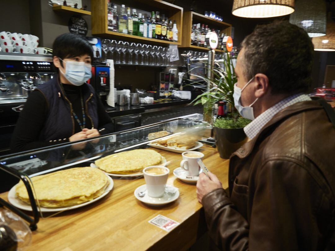 Una camarera de origen oriental atiende a un cliente en un bar español