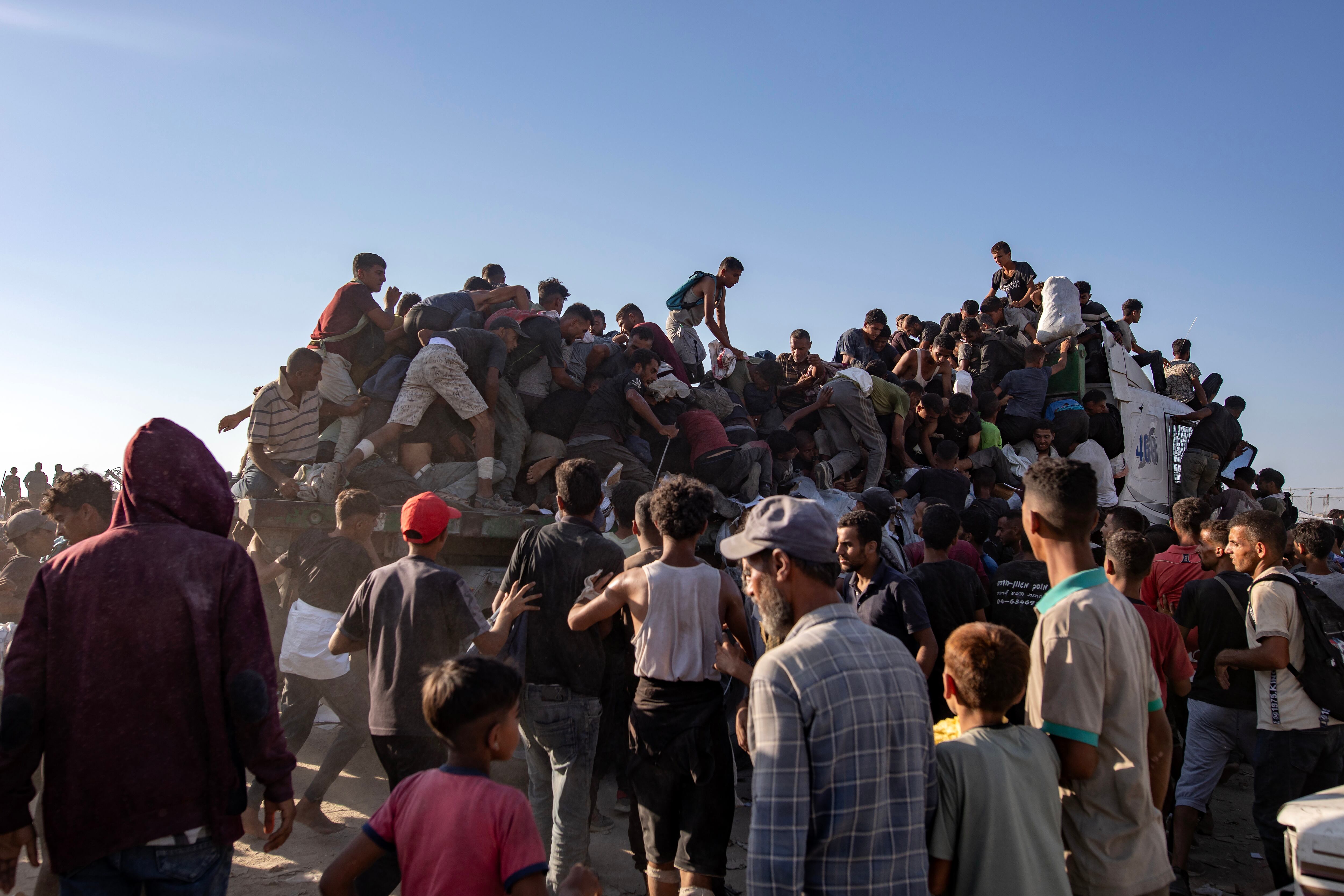 Palestinos desplazados internos suben a camiones de ayuda humanitaria para conseguir comida cerca de un punto de distribución de alimentos en el corredor de Morag, al sur de Jan Yunis, en el sur de la Franja de Gaza, el 4 de agosto de 2025.