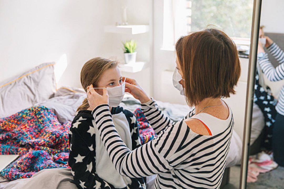 Una madre pone una mascarilla a su hija