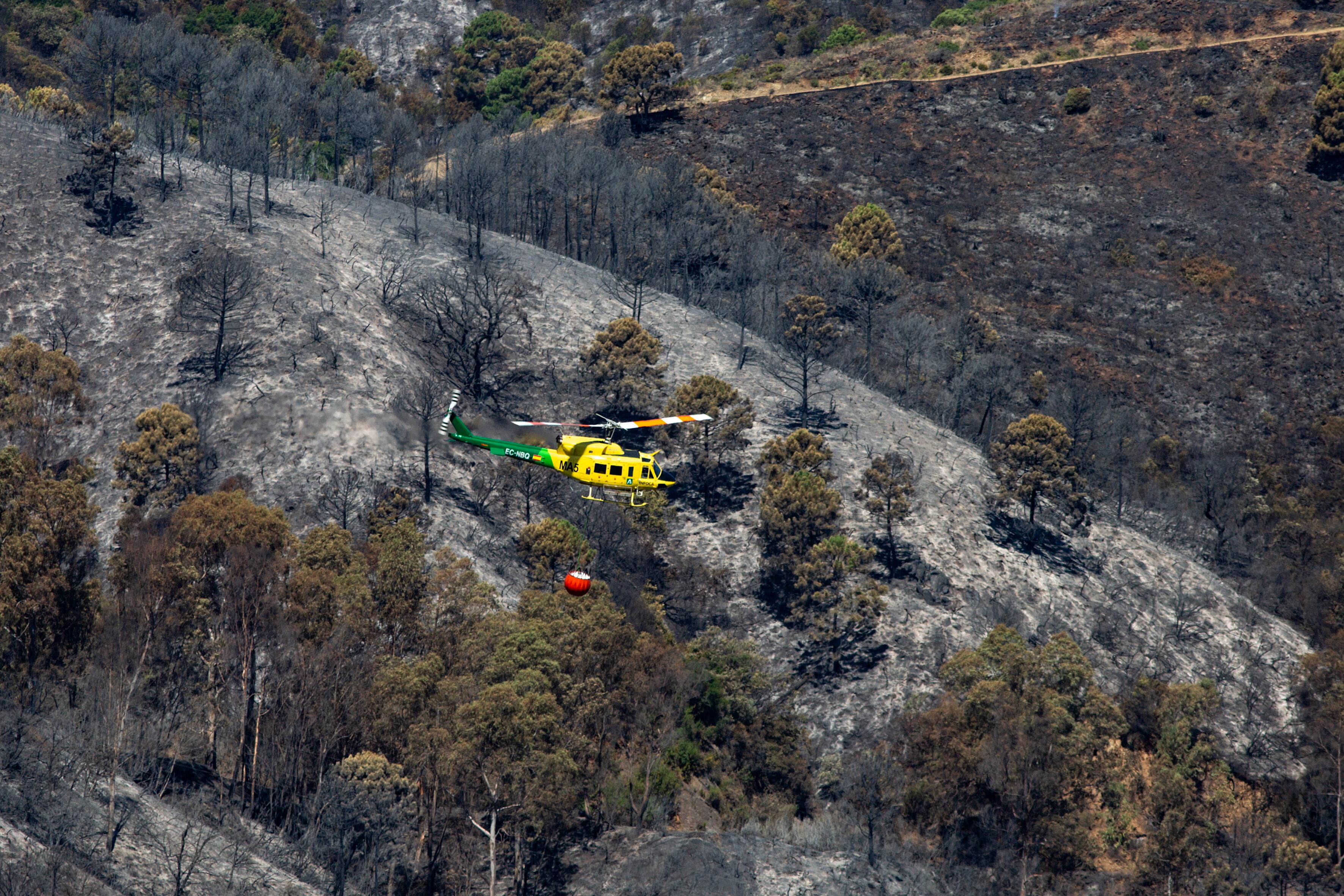 GRAFAND107. BENAHAVÍS (MÄLAGA), 10/06/2022.- Un helicóptero sigue trabajando en la extinción del  incendio forestal de Pujerra (Málaga), declarado este miércoles en el Paraje de la Resinera y que afecta a los municipios de Pujerra, Júzcar y Benahavís, y que según han informado fuentes del Infoca ha quedado estabilizado. EFE/Daniel Pérez
