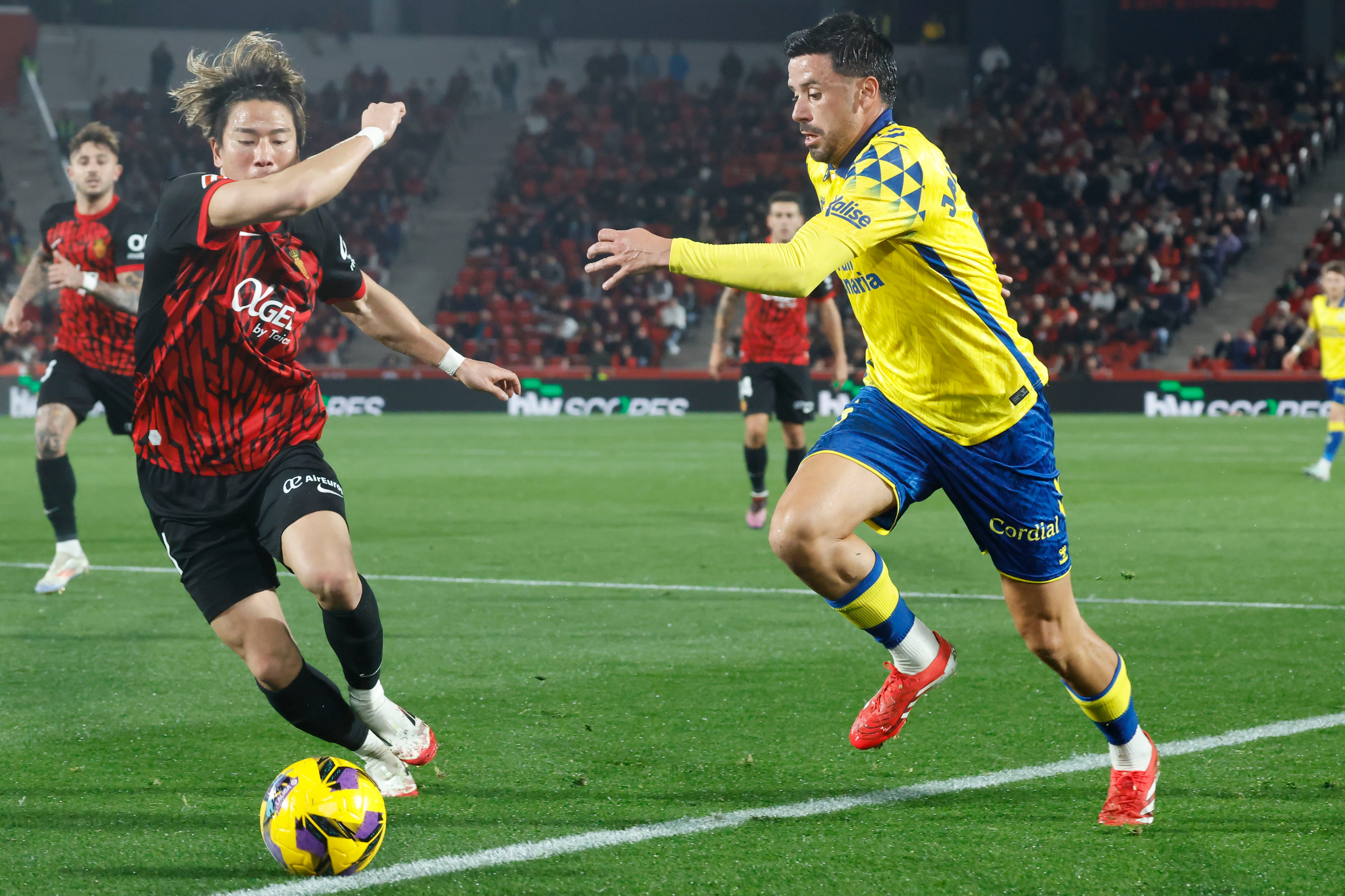 PALMA DE MALLORCA, 16/02/2025.- El centrocampista japonés del Mallorca Takuma Asano (i) lucha con Javier Muñoz, de Las Palmas, durante el partido de la jornada 24 de LaLiga EA Sports entre el RCD Mallorca y la UD Las Palmas, este domingo en el Estadi Mallorca Son Moix .-EFE/ Cati Cladera
