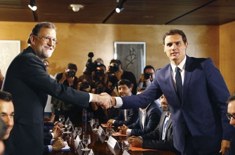 El jefe del Gobierno, Mariano Rajoy y el líder de Ciudadanos, Albert Rivera, se estrechan la mano durante la reunión de sus respectivas delegaciones en la que van a certificar el acuerdo de investidura. 