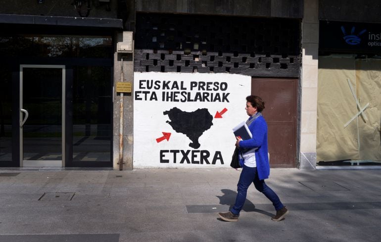 Una mujer camina frente a un cartel en favor de ETA en Amorebieta