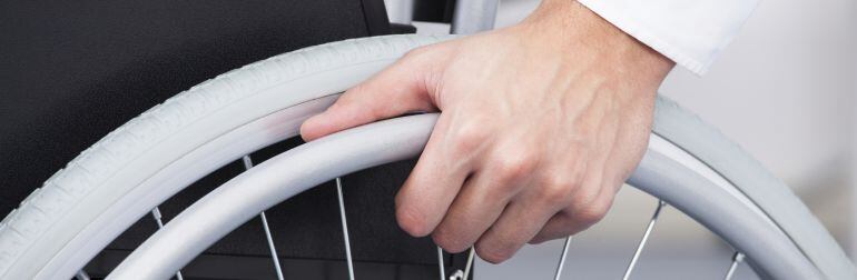 Imagen de la mano de una persona en silla de ruedas