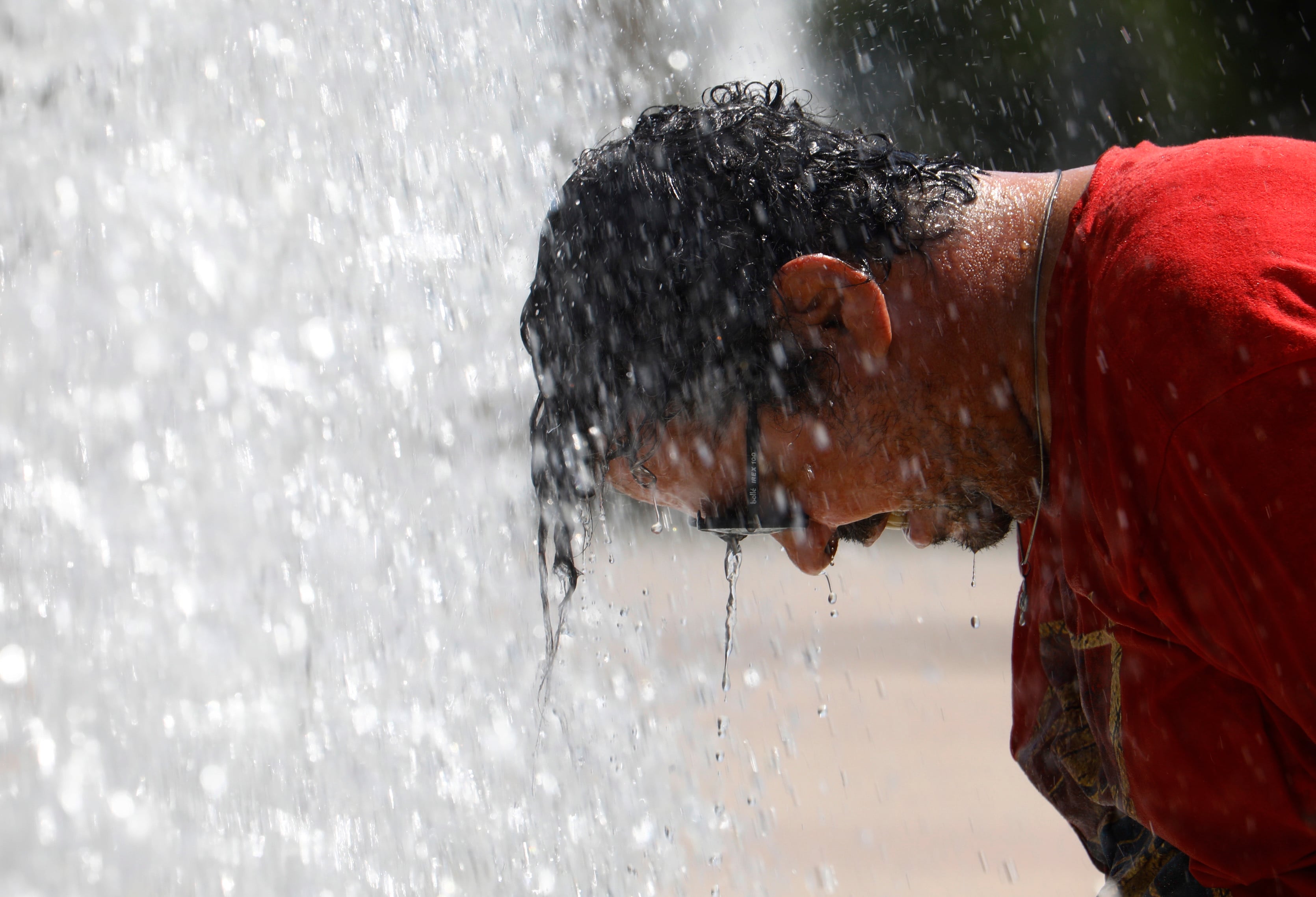 Un hombre se refresca en una fuente de Córdoba.