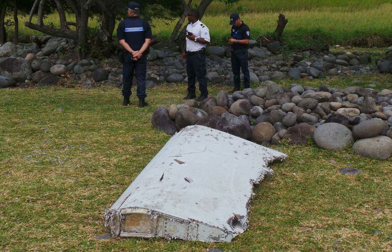 Gerndarmes franceses junto a una de las partes del avión encontradas en la playa de Saint-Andre, en la isla de La Reunión