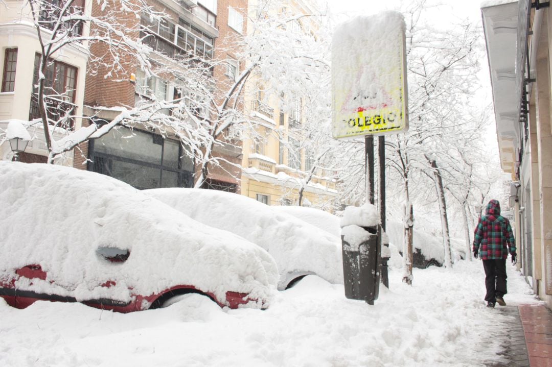 Una persona pasea por una céntrica calle cubierta de nieve junto al acceso de un colegio en Madrid (España) a 9 de enero de 2021.