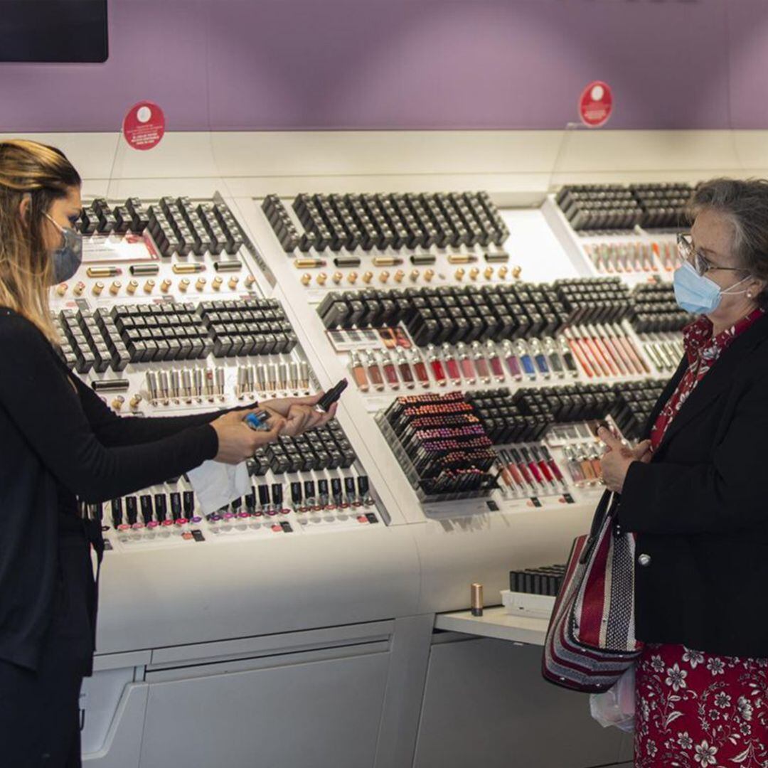 Una empleada de una tienda de cosmética atiende a una clienta durante el segundo día de la fase 1 del plan de desescalada que ha elaborado el Gobierno de España.