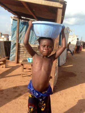 Marie,5 años cargando agua para su baño del día en el campo de desplazados de Mpoko.