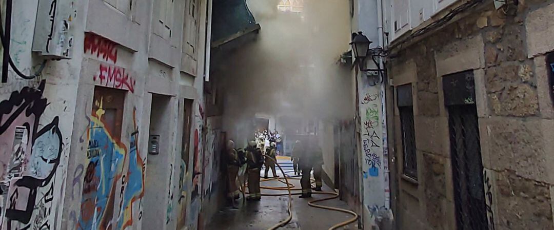 Los bomberos intentan sofocar el fuego en medio de la humareda