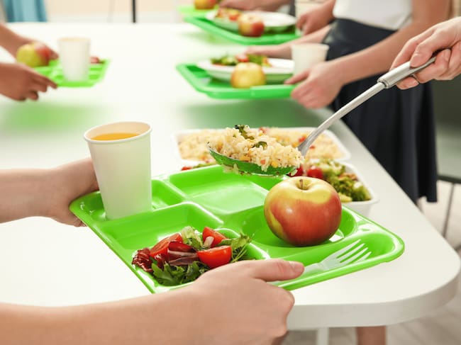 Niño sujetando una bandeja en un comedor escolar
