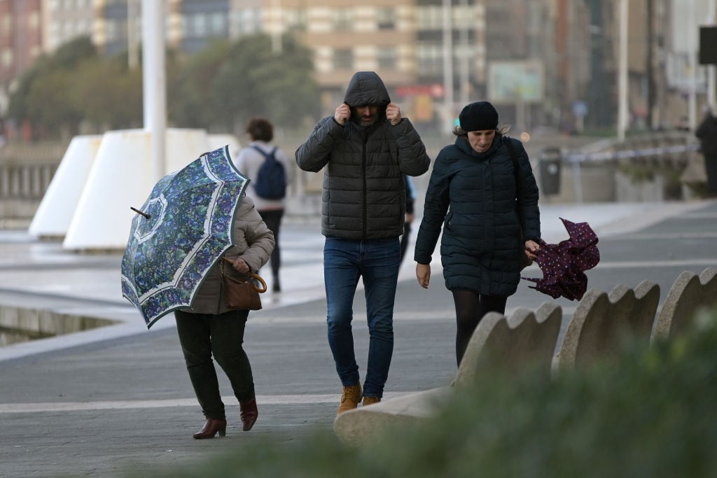 Viandantes de A Coruña se resguardan del frío y la lluvia.