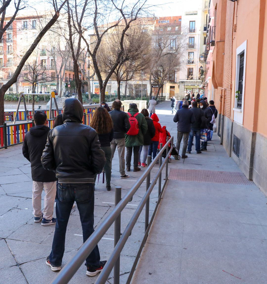 Fila de personas vulnerables para recoger la bolsa de comida.