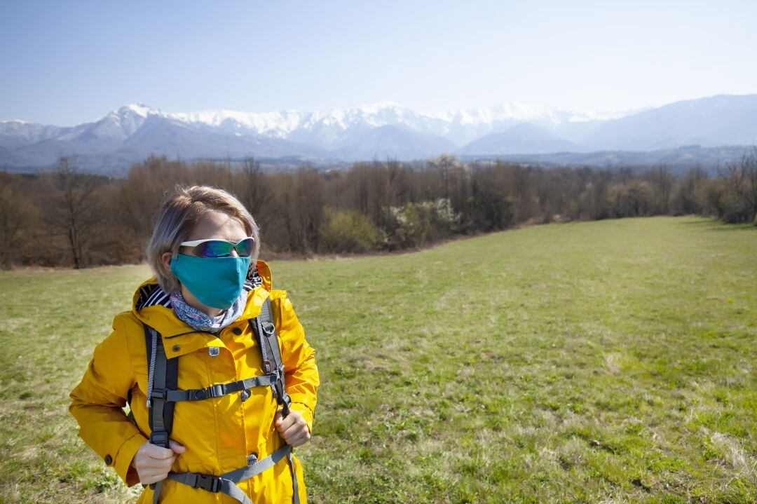 Una mujer con mascarilla en el campo. 