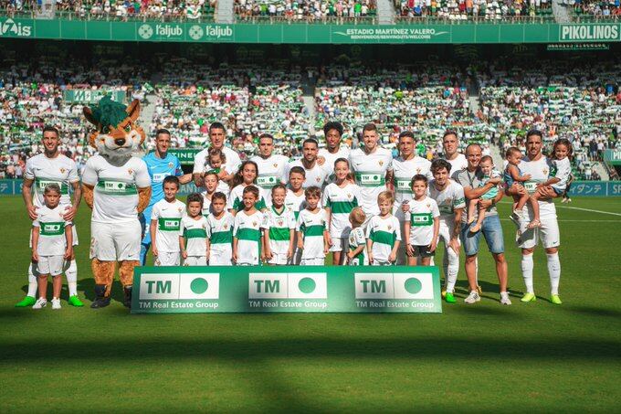 Los jugadores del Elche posan con la mascota, Datigol, y con jóvenes aficionados