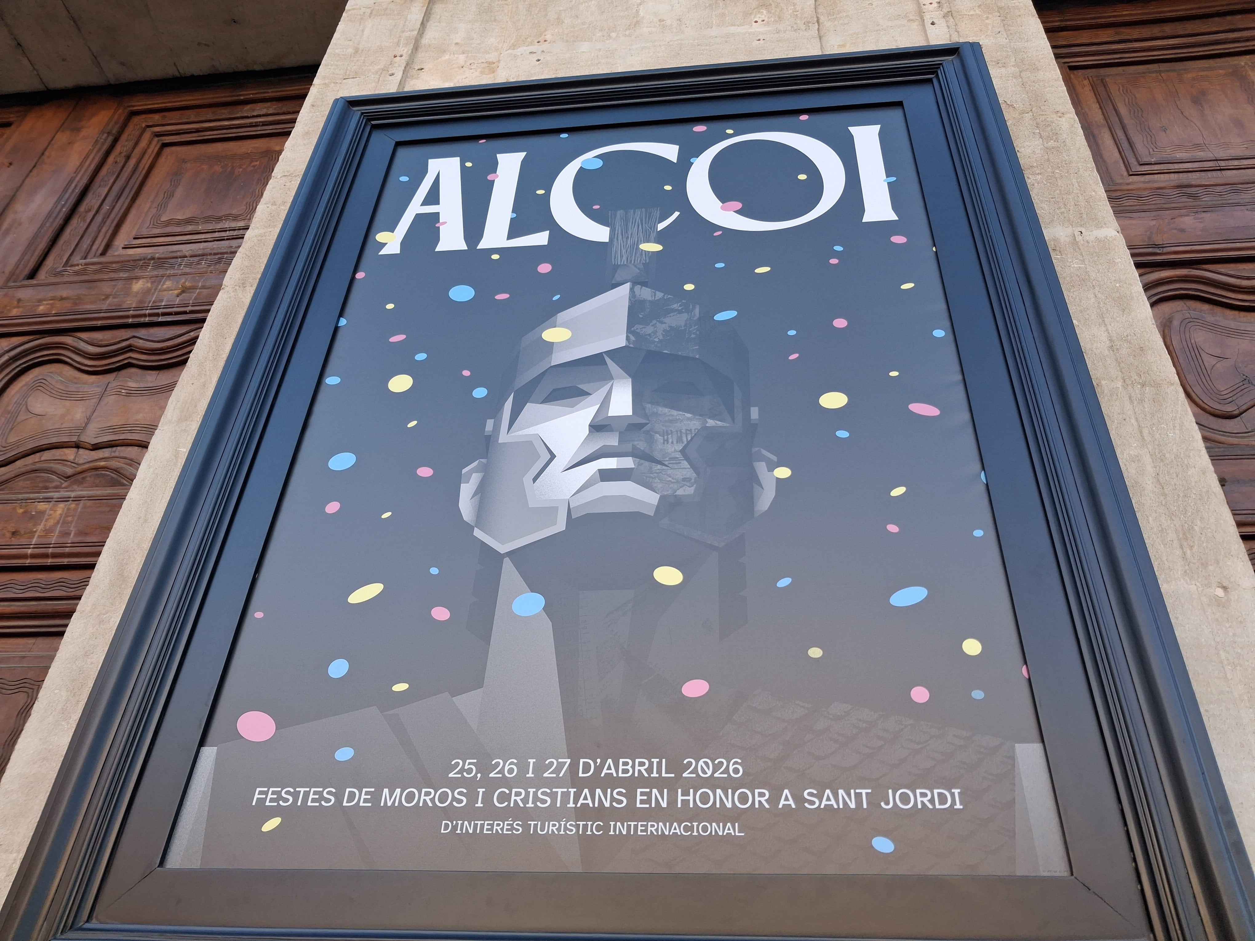 Los alcoyanos y alcoyanas visitan el cartel de las Fiestas de Moros y Cristianos de Alcoy expuesto en la fachada del Ayuntamiento.