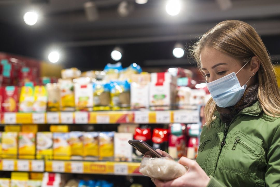 Imagen de una mujer con mascarilla en un supermercado.