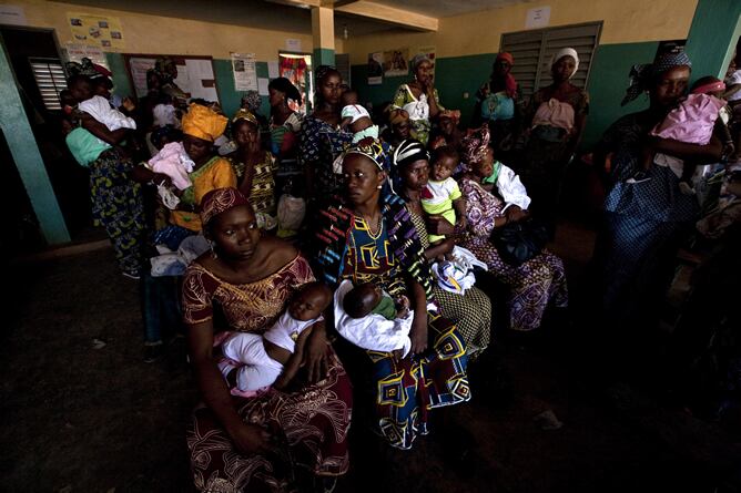 Madres portando a sus hijos en brazos, a la espera de que sean vacunados en el centro de Virimadjo