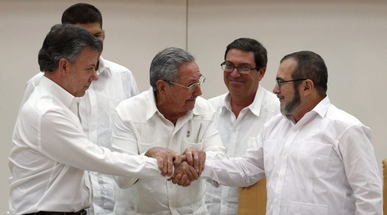 El presidente de Colombia Juan Manuel Santos, el presidente de Cuba Raúl Castro y el máximo líder de las FARC, Rodrigo Londoño, alias &quot;Timochenko&quot;, se dan la mano en un acto en La Habana (Cuba).