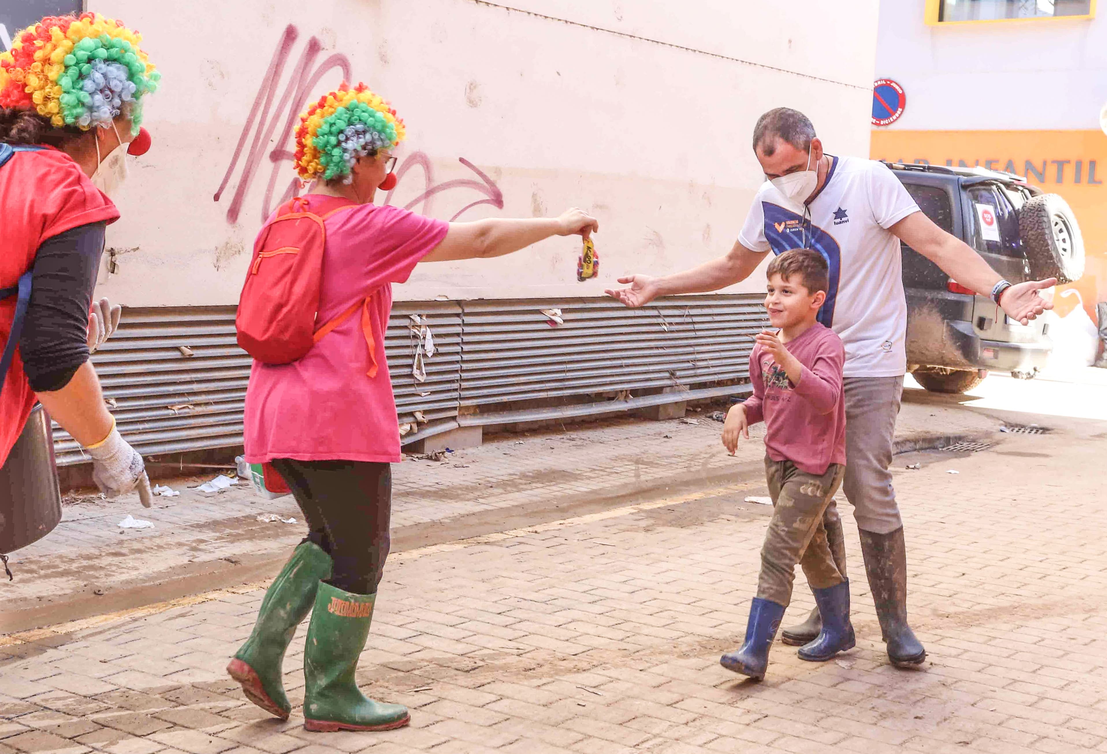 Dos voluntarias eldenses repartiendo una bolsa de chucherías a un niño en Sedaví.