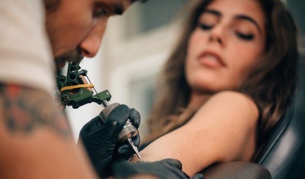 Una mujer se hace un tatuaje. 