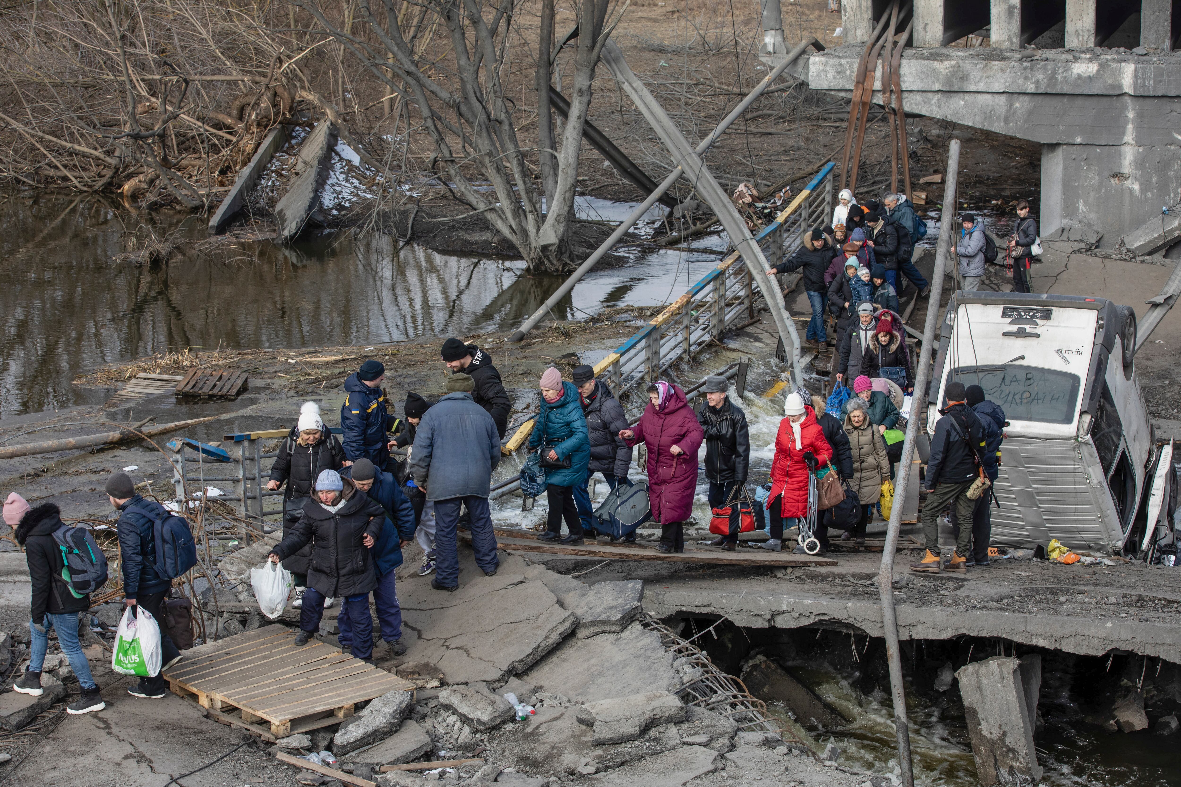 Residents cross the destroyed bridge as they flee from the frontline town of Irpin, Kyiv (Kiev) region, Ukraine, 09 March 2022. Irpin, the town which is located near Kyiv city had heavy fightings for almost a week between Ukrainian and Russian militaries forcing thousands of people to escape from the town.