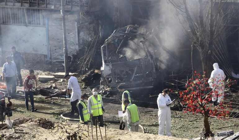 Miembros de las fuerzas de seguridad inspeccionan el lugar tras el atentado suicida con un coche bomba en Kabul (Afganistán). 