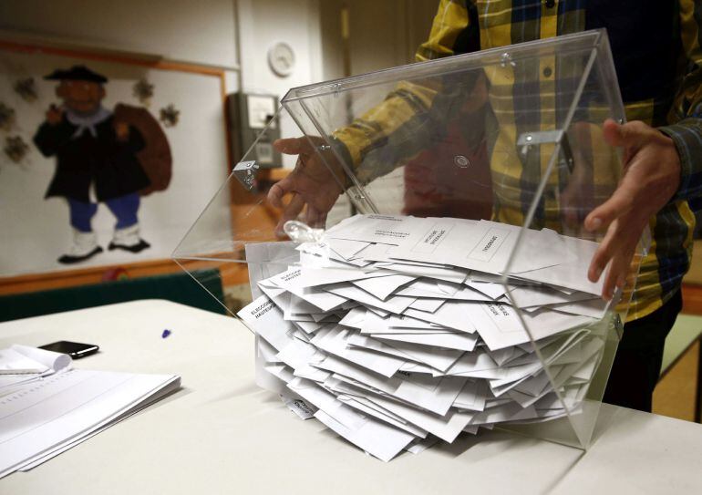 El presidente de una mesa electoral deposita los votos de la urna sobre una mesa para proceder a su recuento