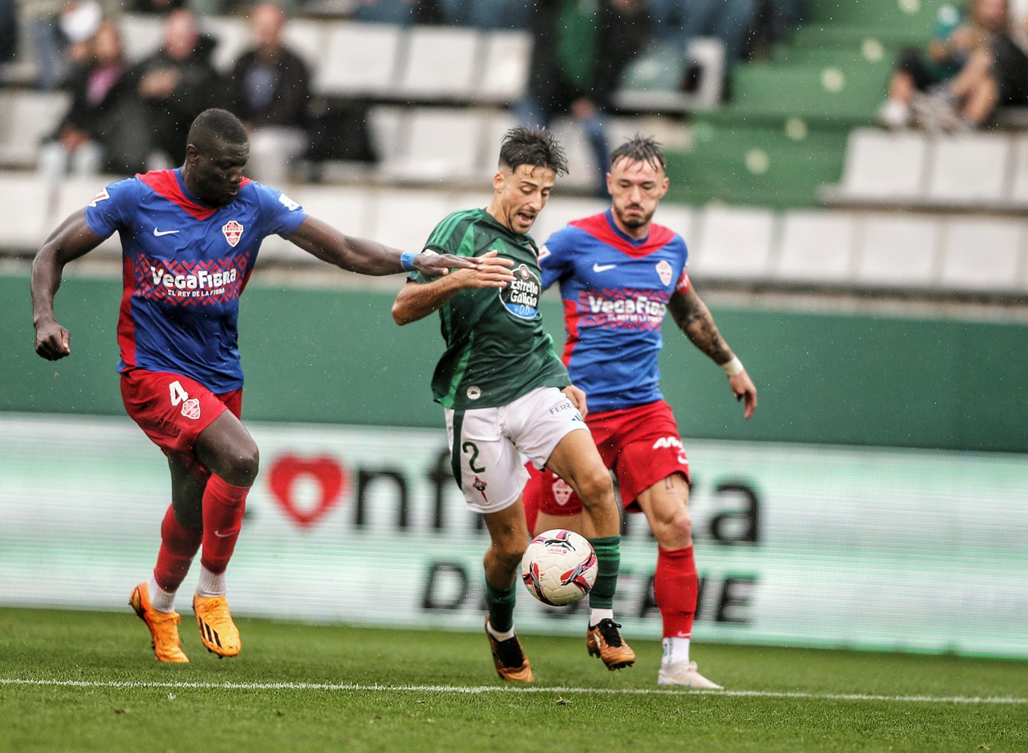 Julián Delmás, entre dos rivales, en una acción del Racing-Elche en A Malata (foto: Cadena SER)