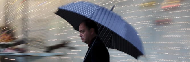 Un hombre se protege de la lluvia con un paraguas en el centro de Valencia