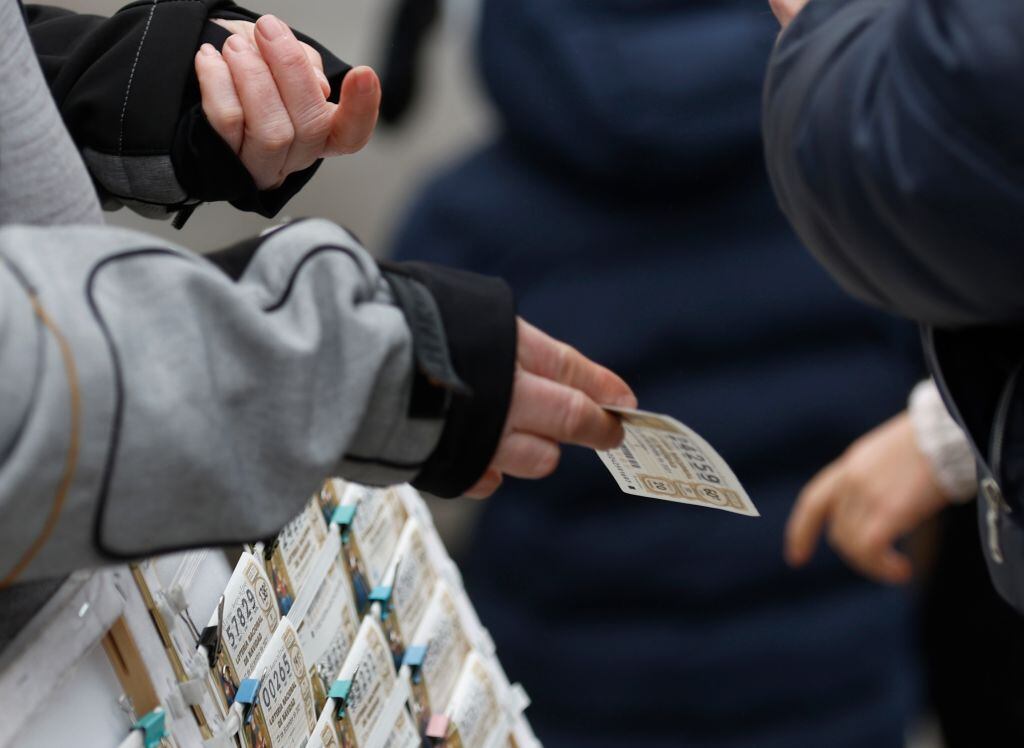 Un vendedor ofrece un décimo de Lotería de Navidad a un cliente.